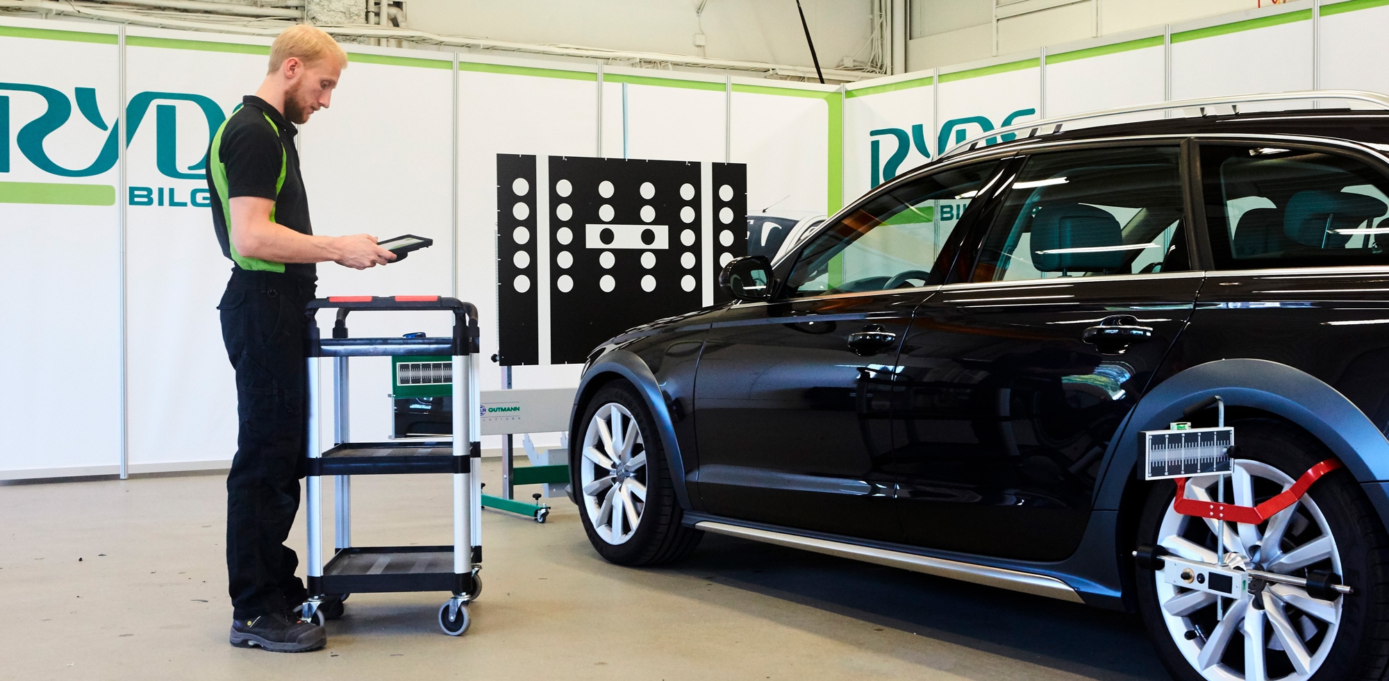 Rydsbilglas kalibrering Rydsbilglas anställd man står och kalibrerar en bil med en läsplatta