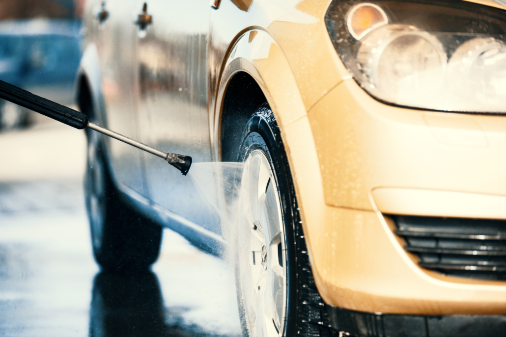 Young,Handsome,Man,Is,Washing,Car,Outdoor. Gul bil som får fälgen tvättat av en högtrycks spruta