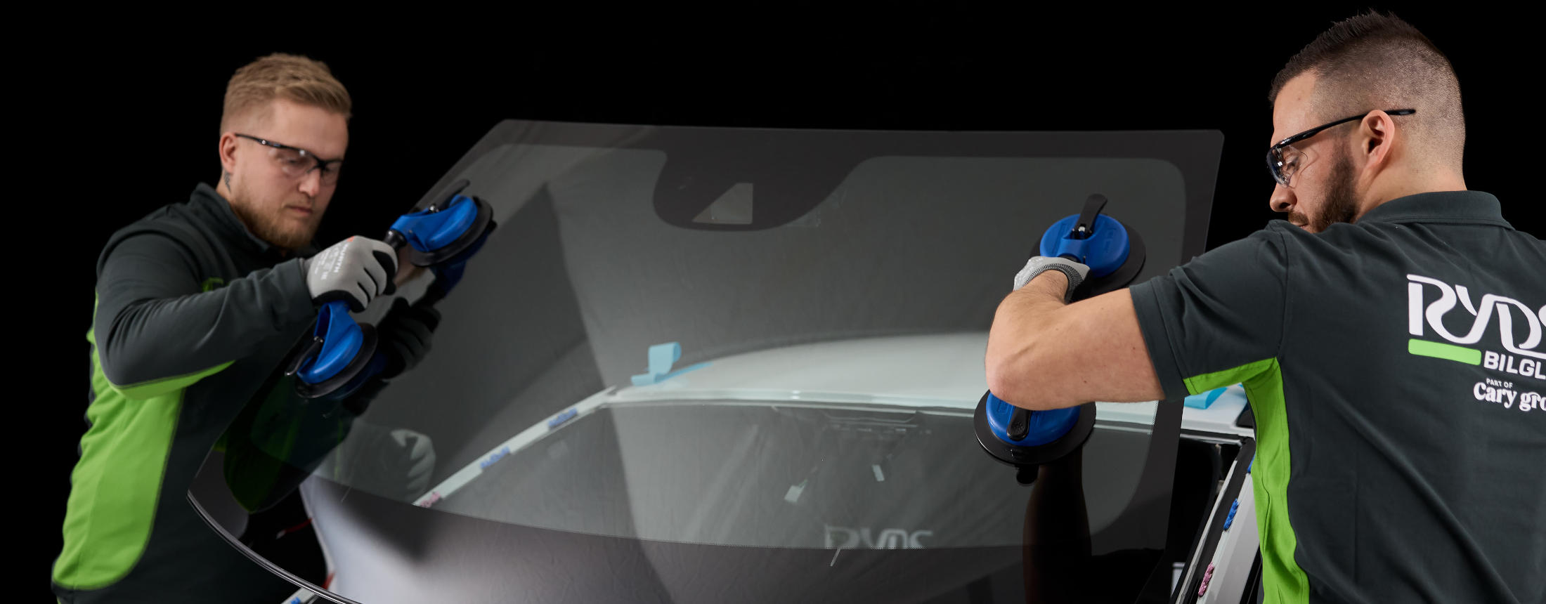 Byta vindruta 2 Ryds anställda män använder verktyg för att lossa på en vindruta